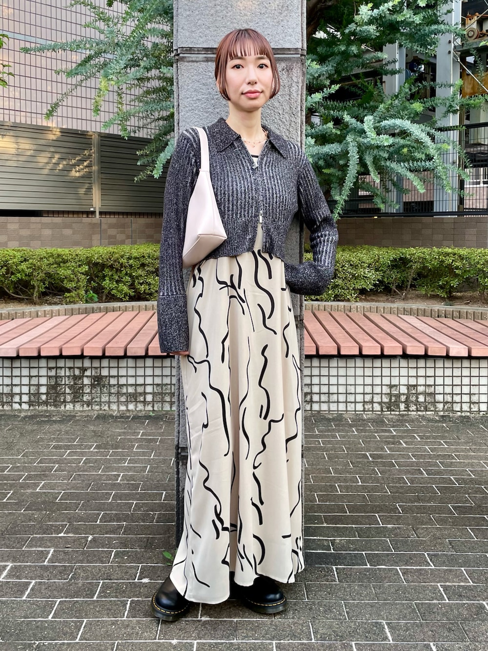 ブラック系のニット/セーター、ホワイト系のワンピース、ブラック系のブーツを着用したレディースの秋コーディネートの2枚目の写真