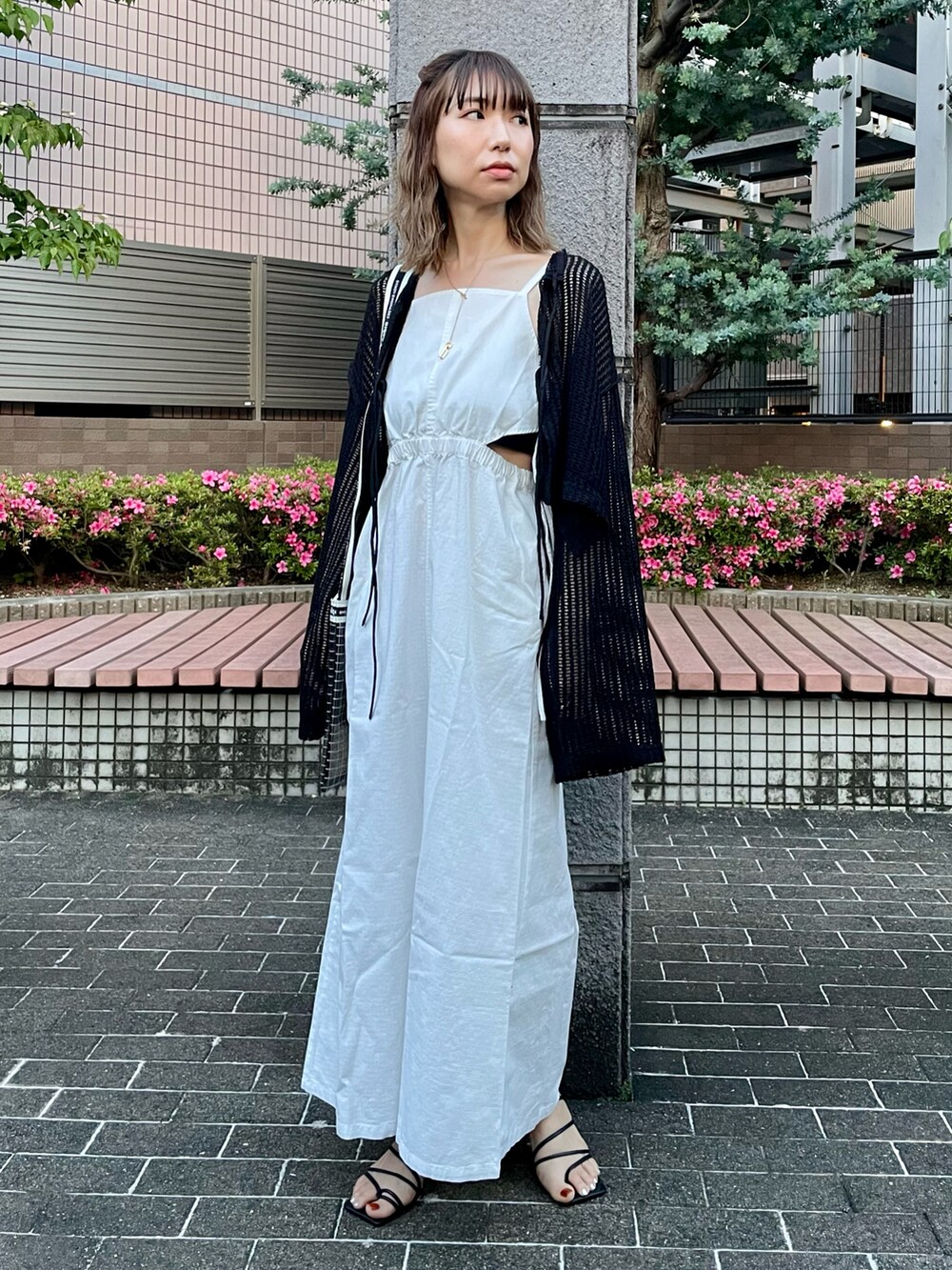 ホワイト系のワンピース、ブラック系のカーディガン/ボレロ、ブラック系のサンダルを着用したレディースの春コーディネートの2枚目の写真