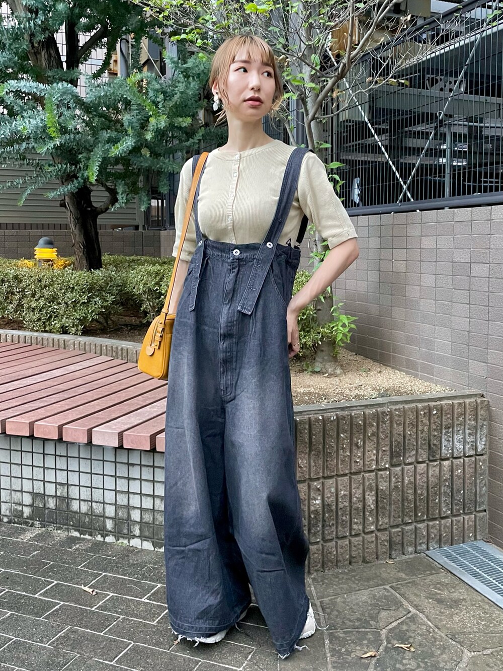 ブラック系のサロペット/オーバーオール、ホワイト系のカーディガン/ボレロ、ベージュ系のスニーカーを着用したレディースの秋コーディネートの2枚目の写真