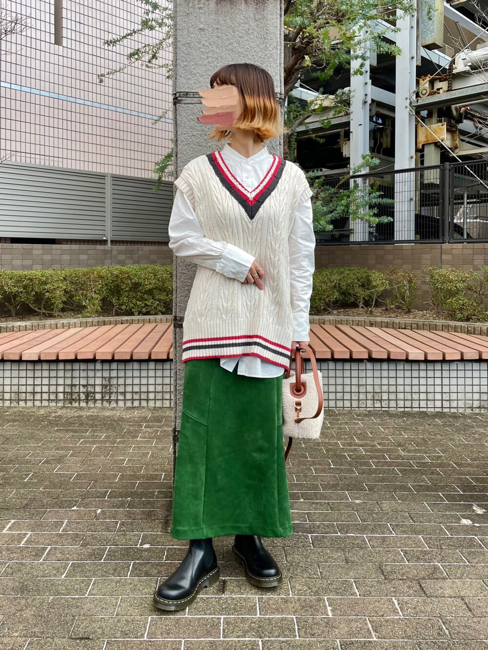 ブラック系のブルゾン、グリーン系のスカート、ホワイト系のショルダーバッグを着用したレディースの冬コーディネートの2枚目の写真