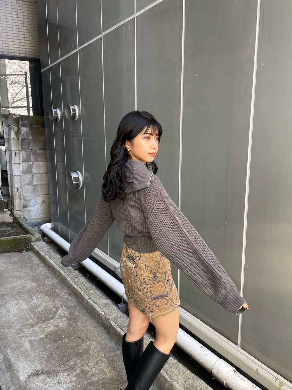 グレー系のニット/セーター、ブラウン系のスカート、ブラック系のブーツを着用したレディースの冬コーディネートの3枚目の写真