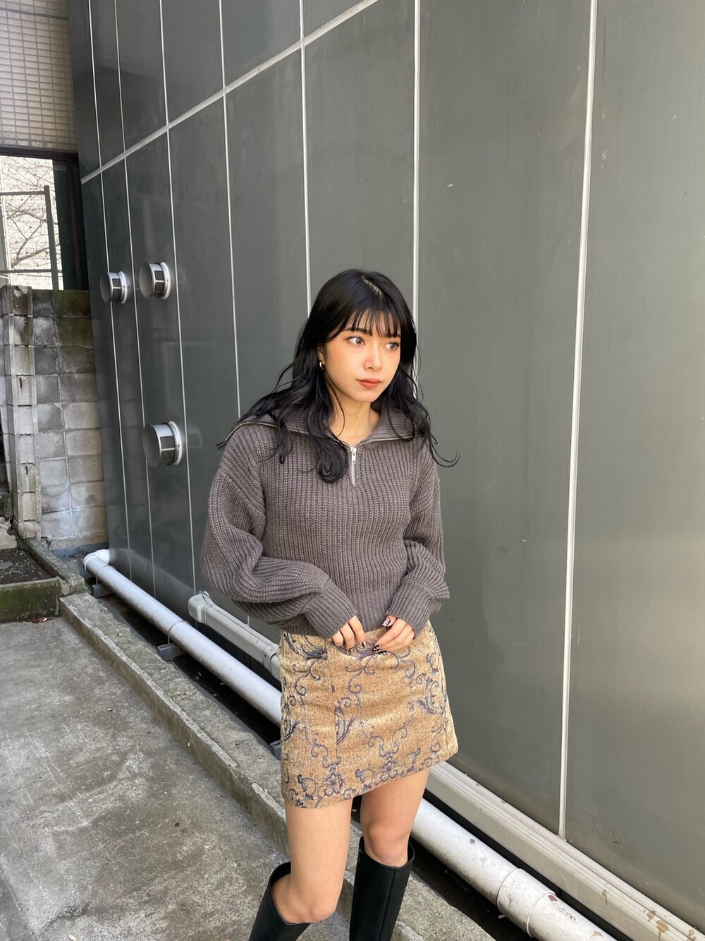 グレー系のニット/セーター、ブラウン系のスカート、ブラック系のブーツを着用したレディースの冬コーディネートの2枚目の写真