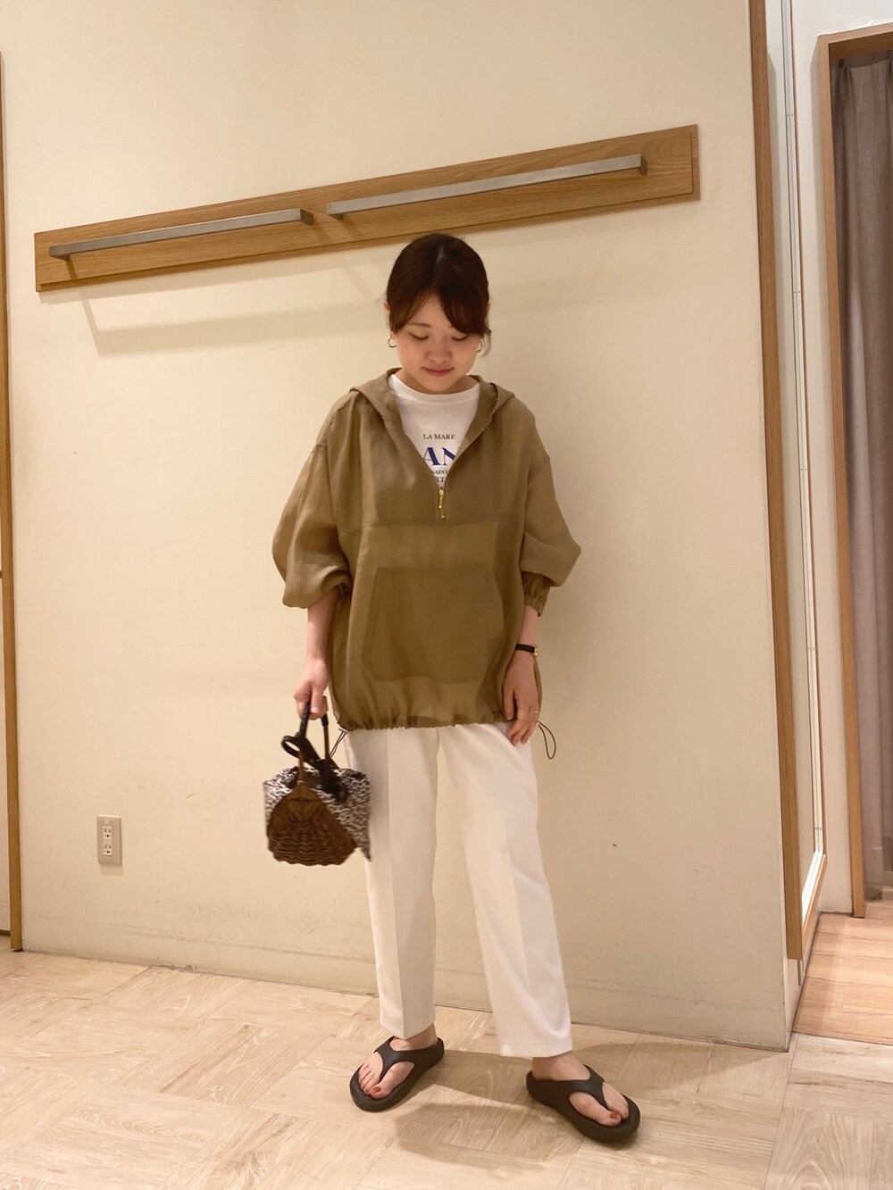 ブラック系のサンダル、ホワイト系のスラックス、ブラウン系のかごバッグを着用したレディースの春コーディネートの2枚目の写真