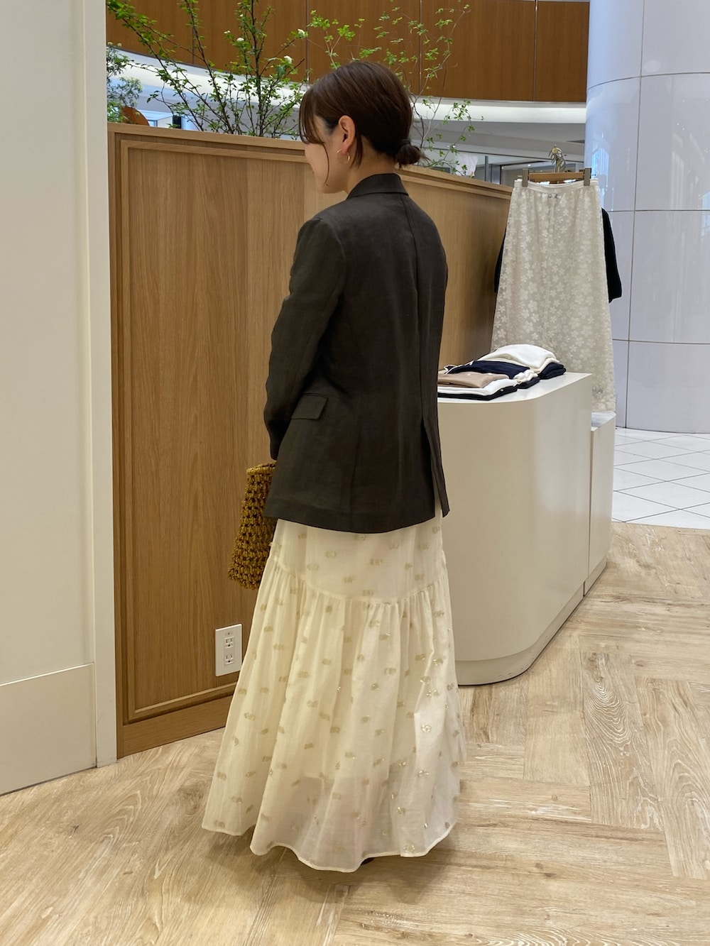 ブラウン系のテーラードジャケット、ベージュ系のかごバッグ、ブラウン系のサンダルを着用したレディースの春コーディネートの4枚目の写真