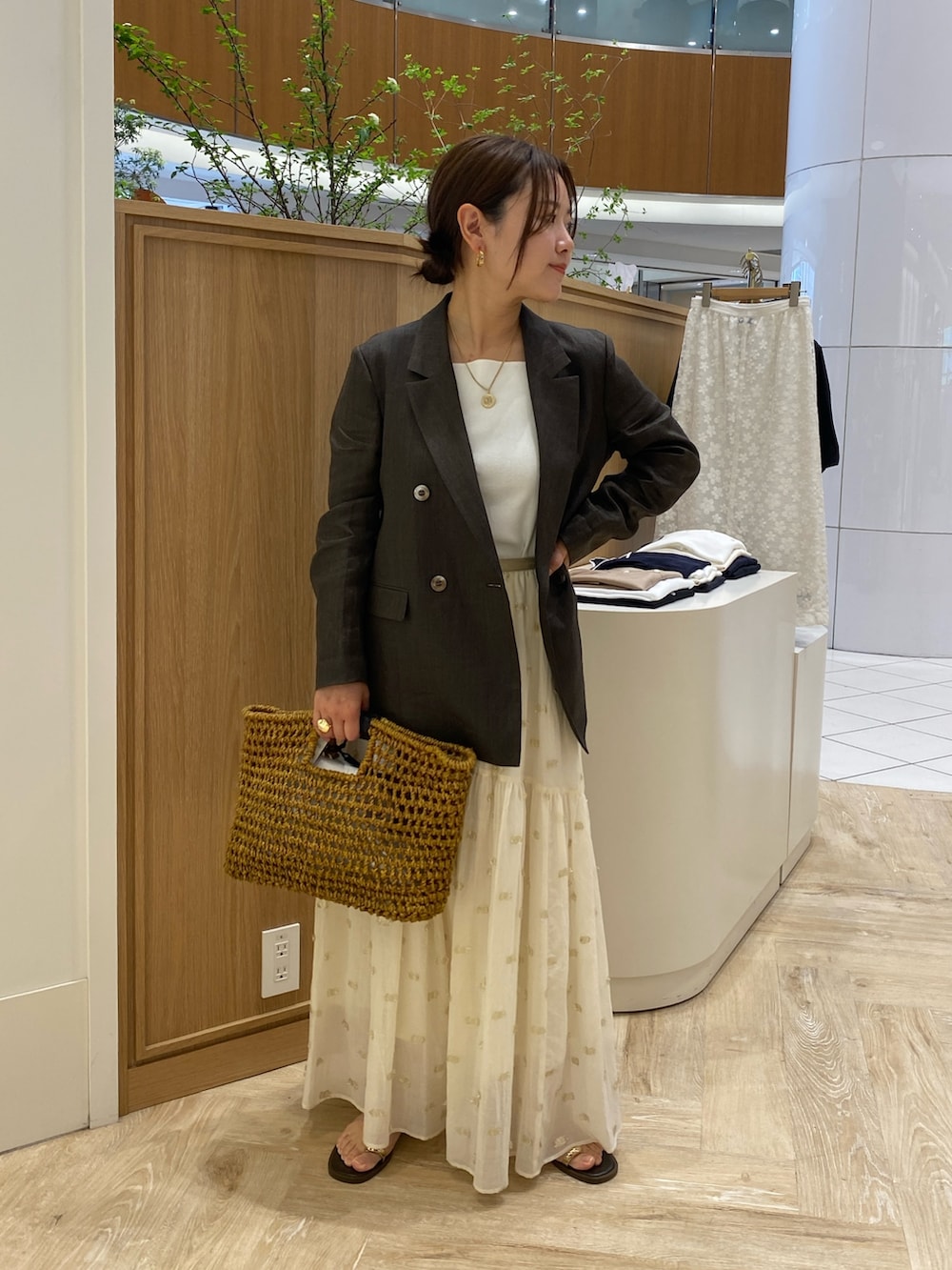 ブラウン系のテーラードジャケット、ベージュ系のかごバッグ、ブラウン系のサンダルを着用したレディースの春コーディネートの3枚目の写真