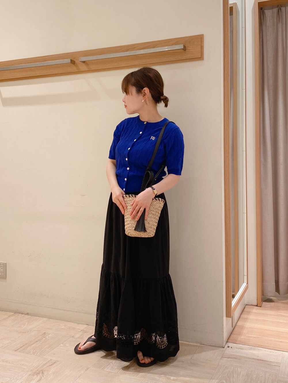 ブラック系のスカート、ブラック系のサンダル、ブラック系のかごバッグを着用したレディースの春コーディネートの2枚目の写真