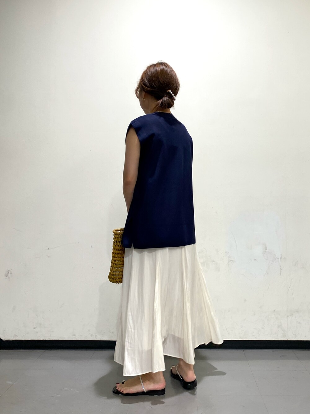 ベージュ系のかごバッグ、ブラウン系のサンダル、ブルー系のベストを着用したレディースの夏コーディネートの3枚目の写真