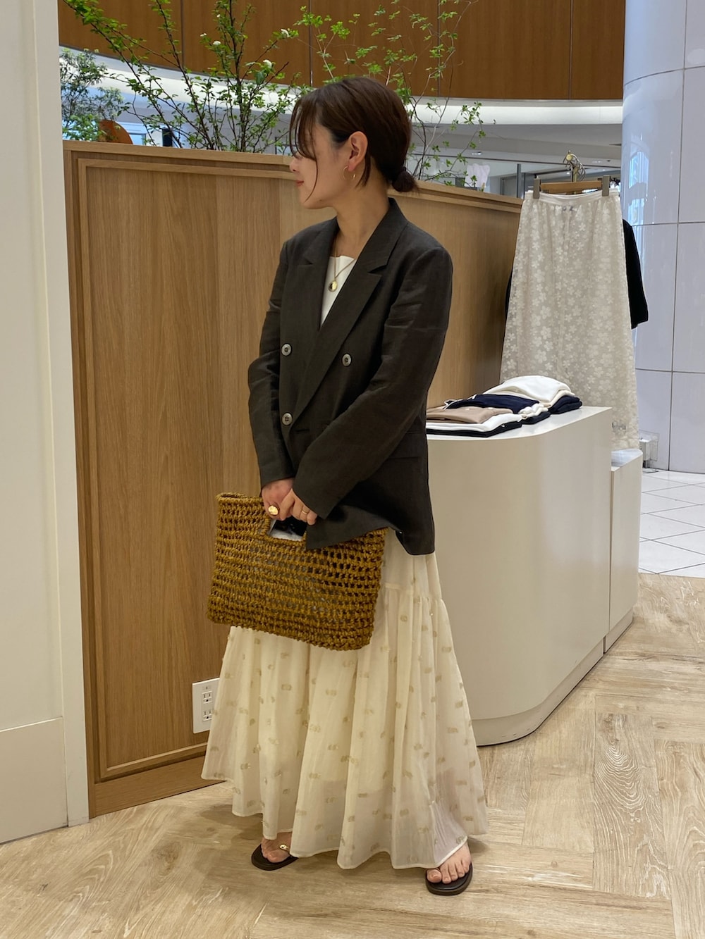 ブラウン系のテーラードジャケット、ベージュ系のかごバッグ、ブラウン系のサンダルを着用したレディースの春コーディネートの2枚目の写真