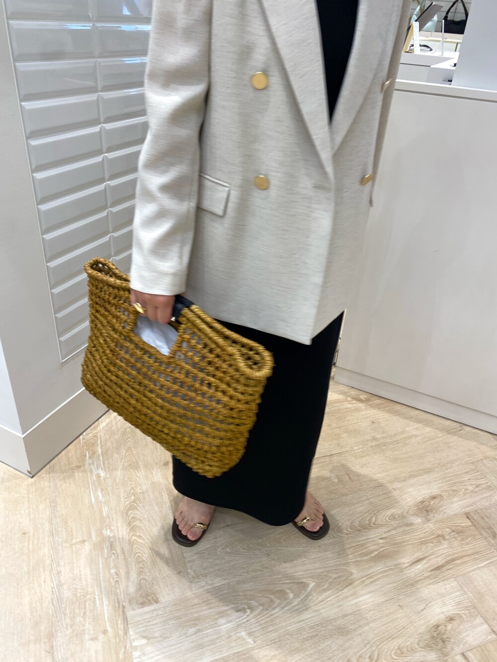 ベージュ系のテーラードジャケット、ブラック系のワンピース、ベージュ系のかごバッグを着用したレディースの春コーディネートの2枚目の写真