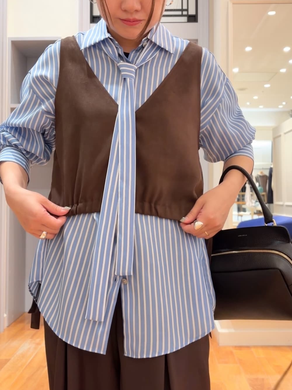 ブルー系のシャツ/ブラウス、ブラウン系のベスト、ブラウン系のその他パンツを着用したレディースの秋コーディネートの4枚目の写真