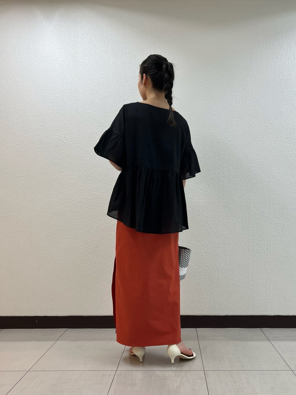 ブラック系のシャツ/ブラウス、オレンジ系のスカートを着用したレディースの春コーディネートの2枚目の写真