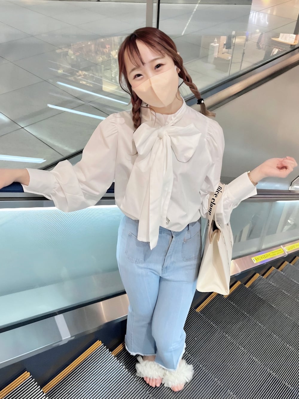ピンク系のトレンチコート、ブルー系のデニムパンツ、ホワイト系のサンダルを着用したレディースの春コーディネートの3枚目の写真