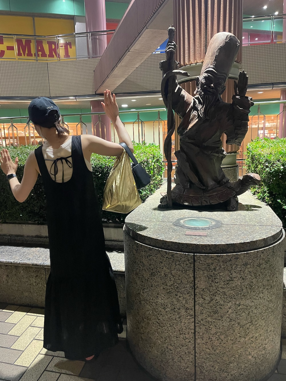 ブラック系のワンピース、ブラック系のサンダル、ブラック系のハンドバッグを着用したレディースの夏コーディネートの2枚目の写真