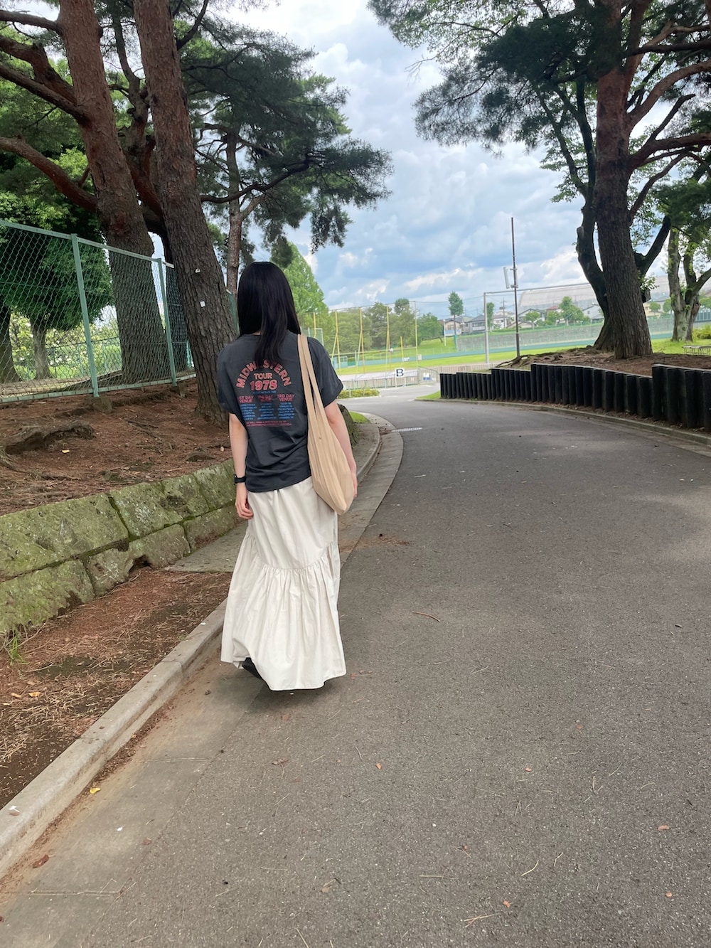 ホワイト系のスカート、グレー系のTシャツ/カットソー、ホワイト系のサンダルを着用したレディースの夏コーディネートの2枚目の写真