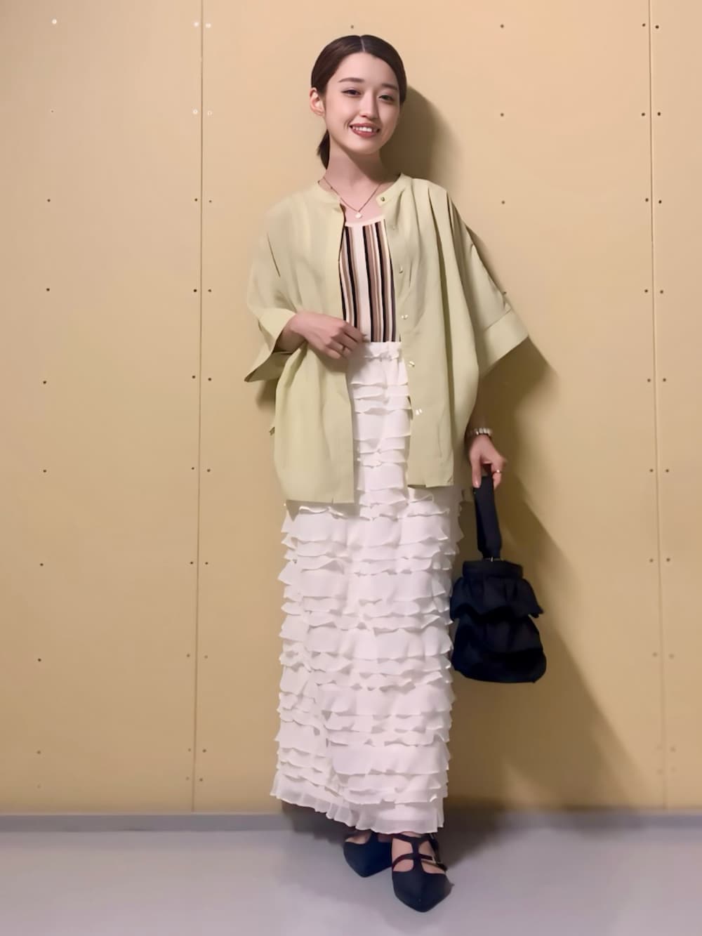 イエロー系のシャツ/ブラウス、ベージュ系のタンクトップ、ホワイト系のスカートを着用したレディースの夏コーディネートの2枚目の写真