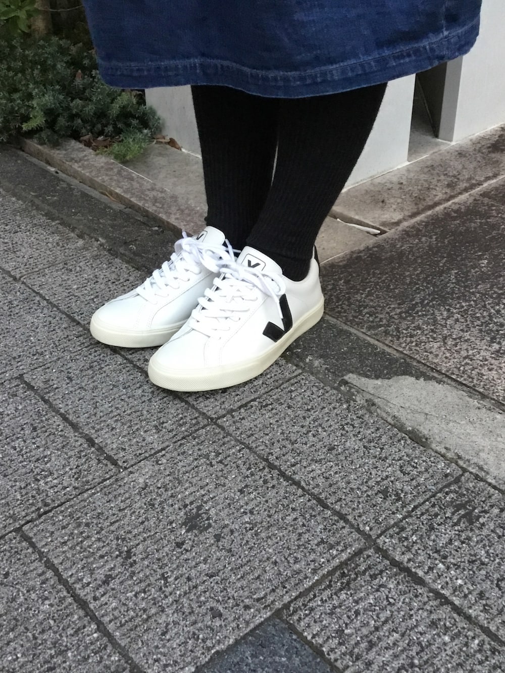 ブラック系のダウンベスト、ブルー系のワンピース、ホワイト系のスニーカーを着用したレディースの冬コーディネートの2枚目の写真