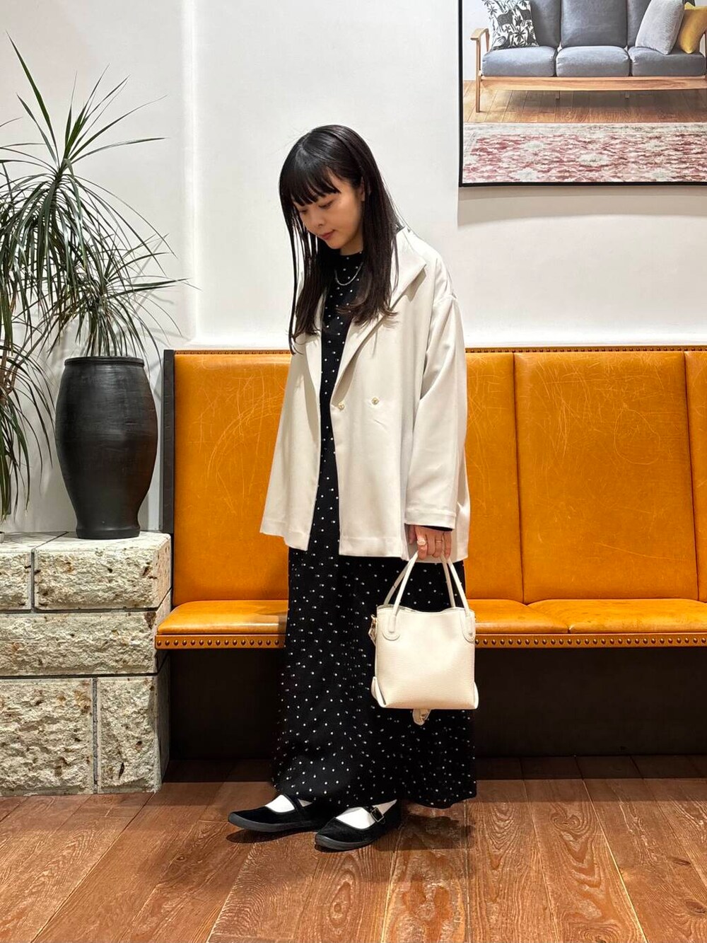 ベージュ系のその他アウター、ホワイト系のショルダーバッグ、ブラック系のワンピースを着用したレディースの春コーディネートの2枚目の写真