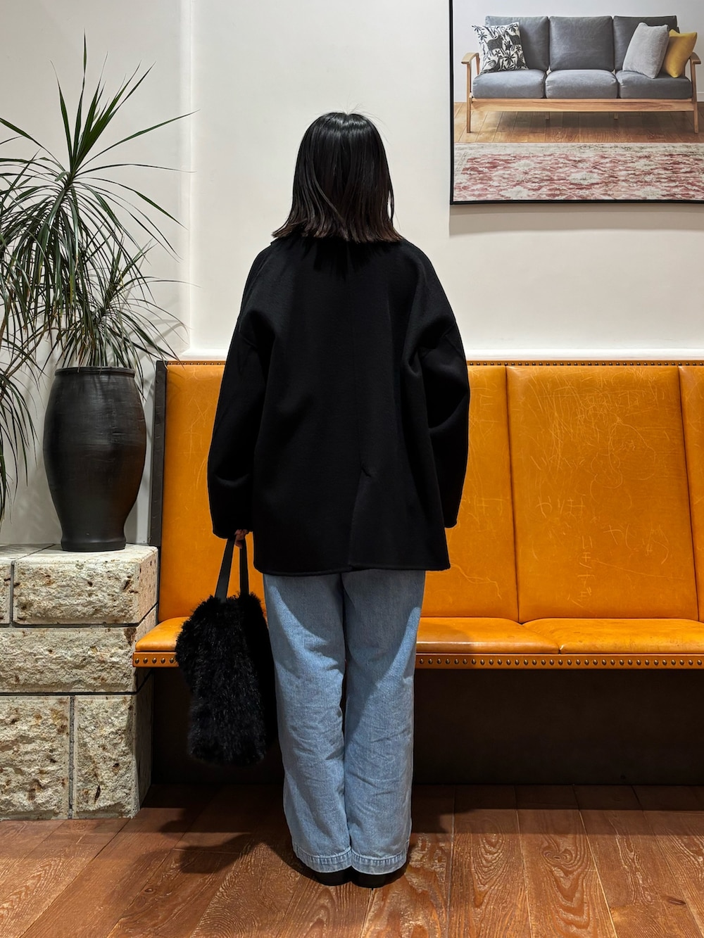 グレー系のニット/セーター、ブラック系のその他アウター、ブルー系のデニムパンツを着用したレディースの秋コーディネートの3枚目の写真