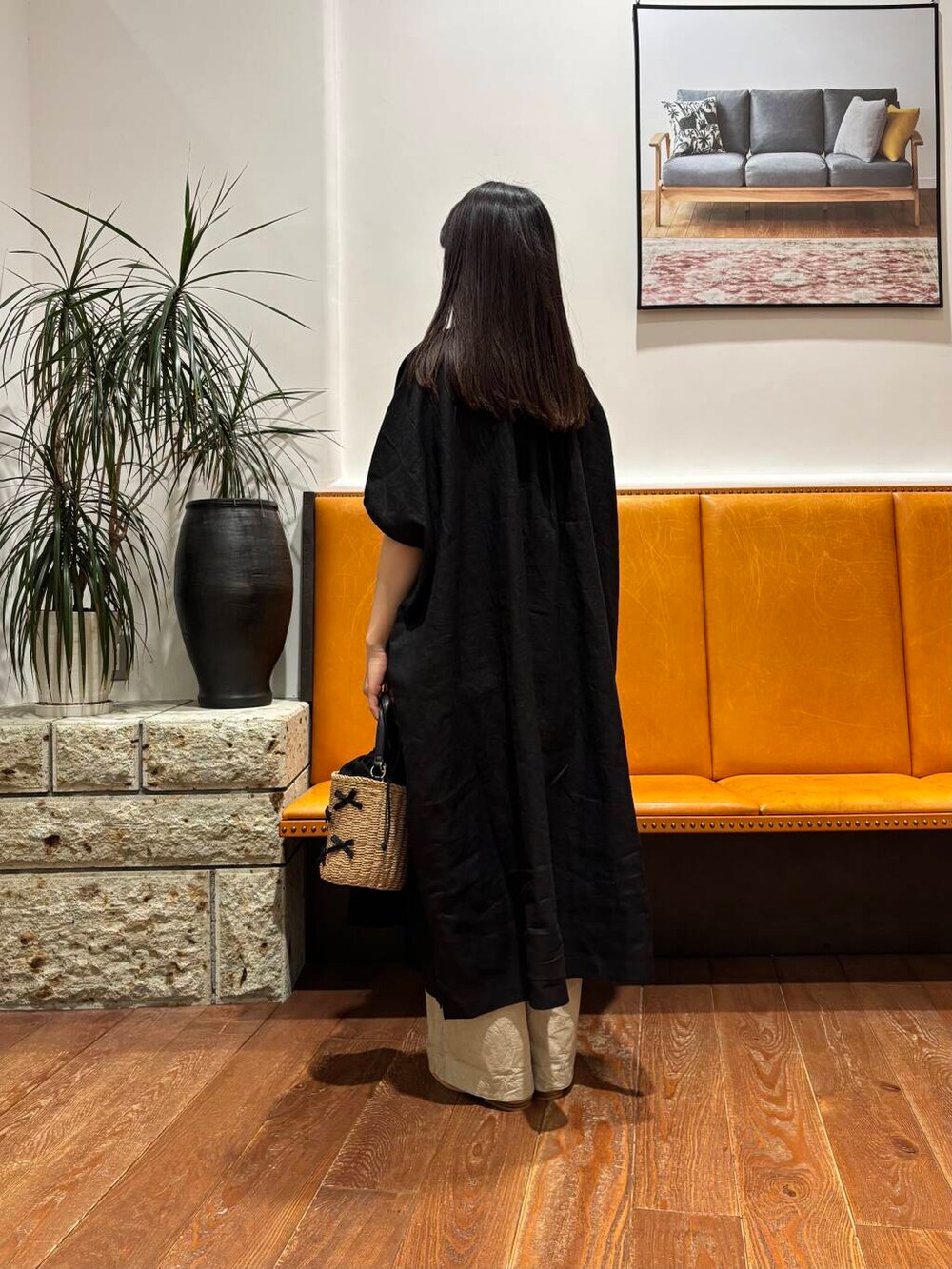 イエロー系のショルダーバッグ、ホワイト系のサンダル、ブラック系のワンピースを着用したレディースの春コーディネートの3枚目の写真