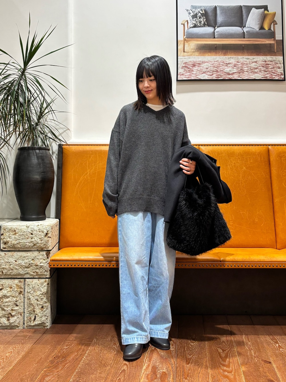 グレー系のニット/セーター、ブラック系のその他アウター、ブルー系のデニムパンツを着用したレディースの秋コーディネートの4枚目の写真