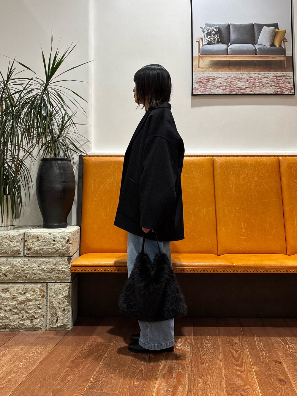 グレー系のニット/セーター、ブラック系のその他アウター、ブルー系のデニムパンツを着用したレディースの秋コーディネートの2枚目の写真