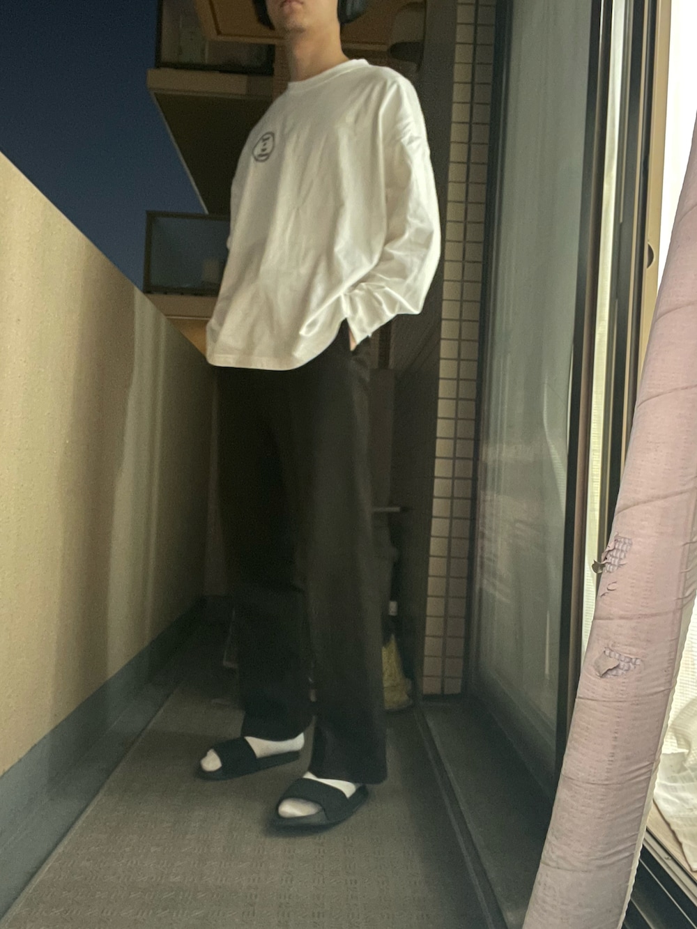 ホワイト系のTシャツ/カットソー、ブラウン系のパンツ、ブラック系のサンダルを着用したメンズの春コーディネートの2枚目の写真