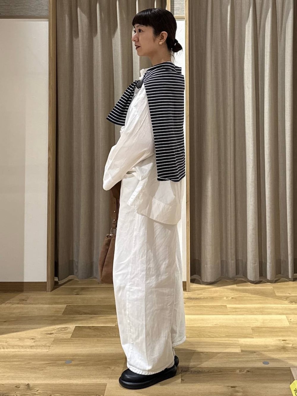 ホワイト系のシャツ/ブラウス、ブラック系のサンダル、ホワイト系のデニムパンツを着用したレディースの春コーディネートの3枚目の写真