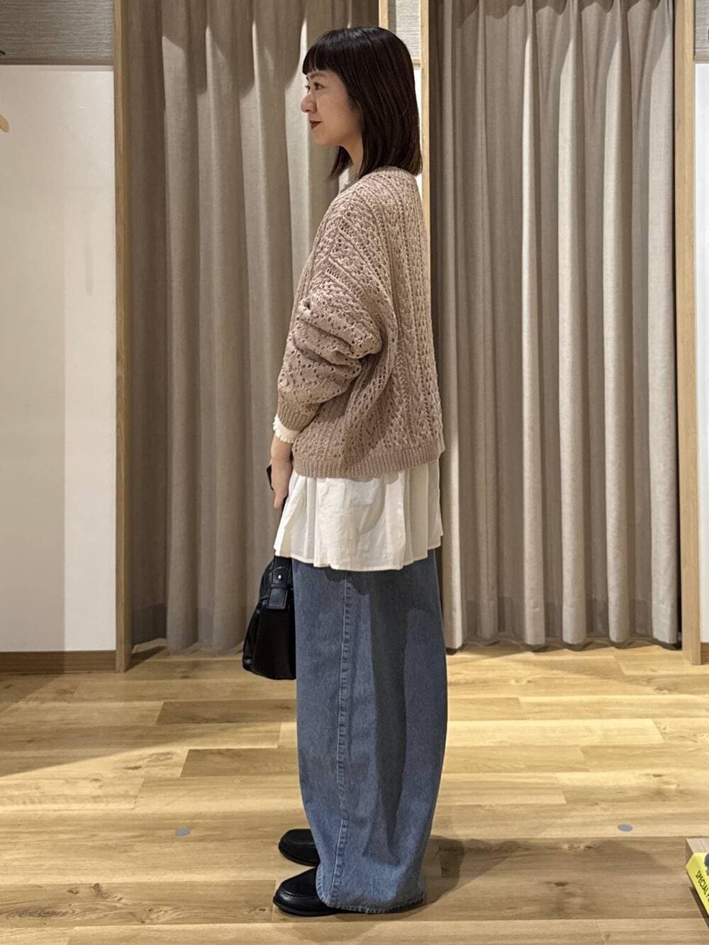 ブルー系のデニムパンツ、ホワイト系のシャツ/ブラウス、ベージュ系のニット/セーターを着用したレディースの冬コーディネートの2枚目の写真