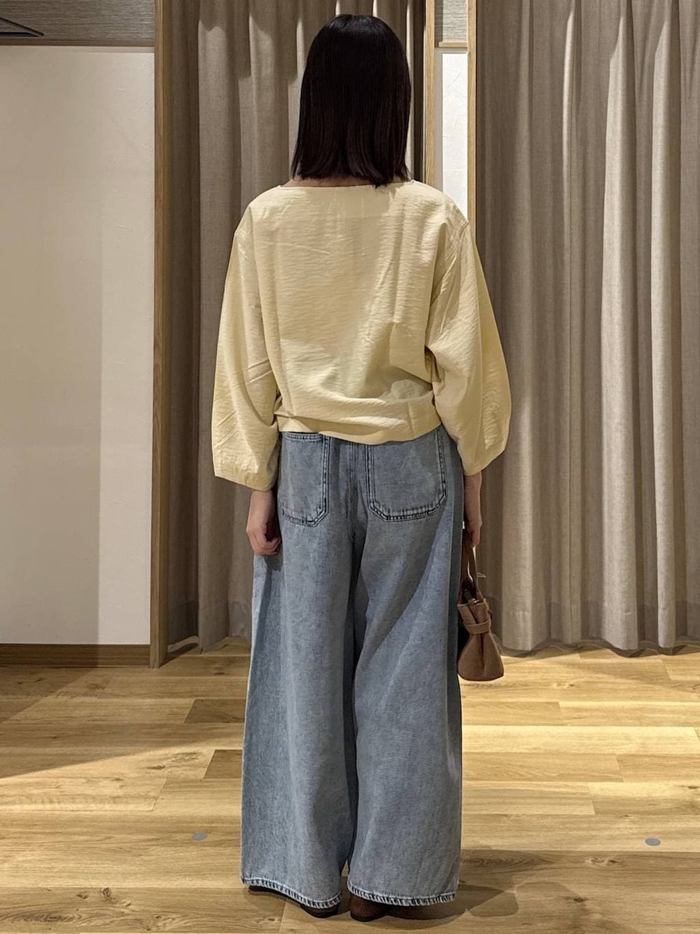 ブルー系のデニムパンツ、ブラウン系のショルダーバッグ、ブラウン系のパンプスを着用したレディースの春コーディネートの3枚目の写真