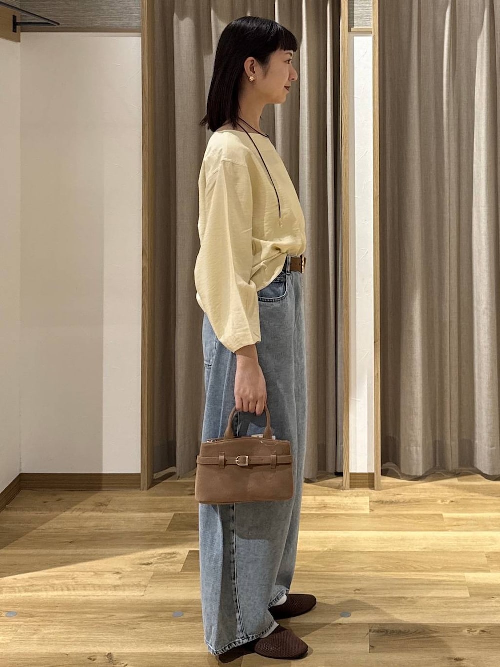 ブルー系のデニムパンツ、ブラウン系のショルダーバッグ、ブラウン系のパンプスを着用したレディースの春コーディネートの4枚目の写真