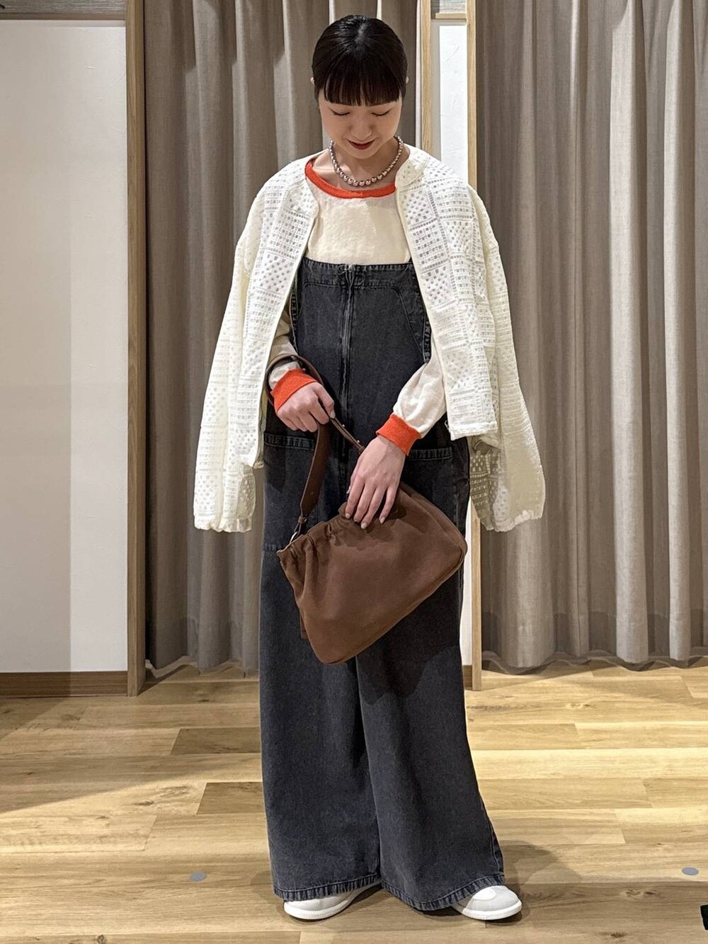 ブラック系のサロペット/オーバーオール、ベージュ系のトートバッグ、ホワイト系のスニーカーを着用したレディースの春コーディネートの2枚目の写真