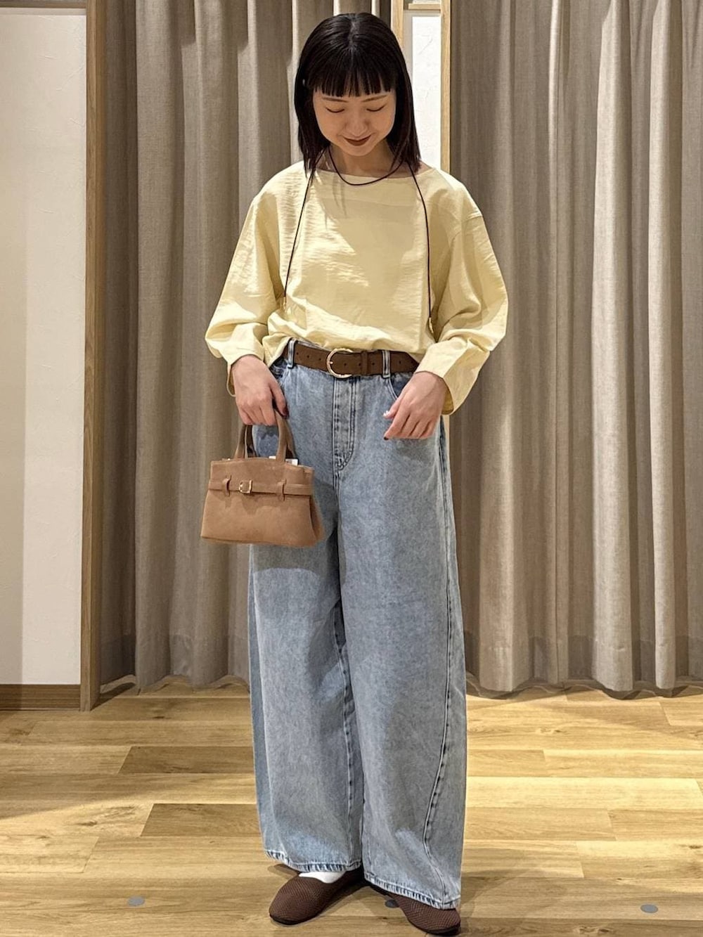 ブルー系のデニムパンツ、ブラウン系のショルダーバッグ、ブラウン系のパンプスを着用したレディースの春コーディネートの5枚目の写真