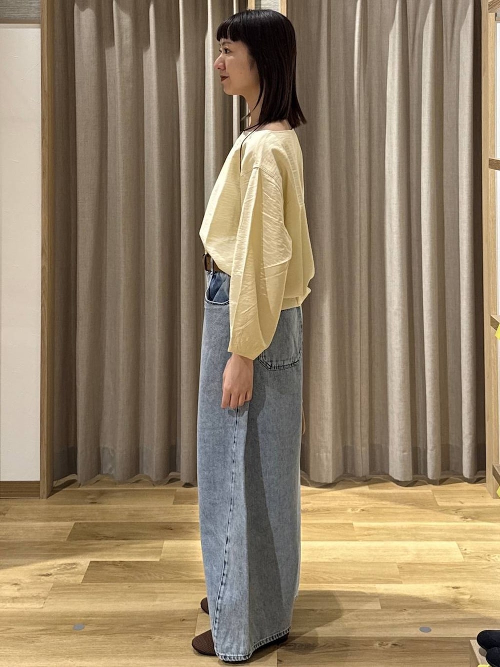 ブルー系のデニムパンツ、ブラウン系のショルダーバッグ、ブラウン系のパンプスを着用したレディースの春コーディネートの2枚目の写真