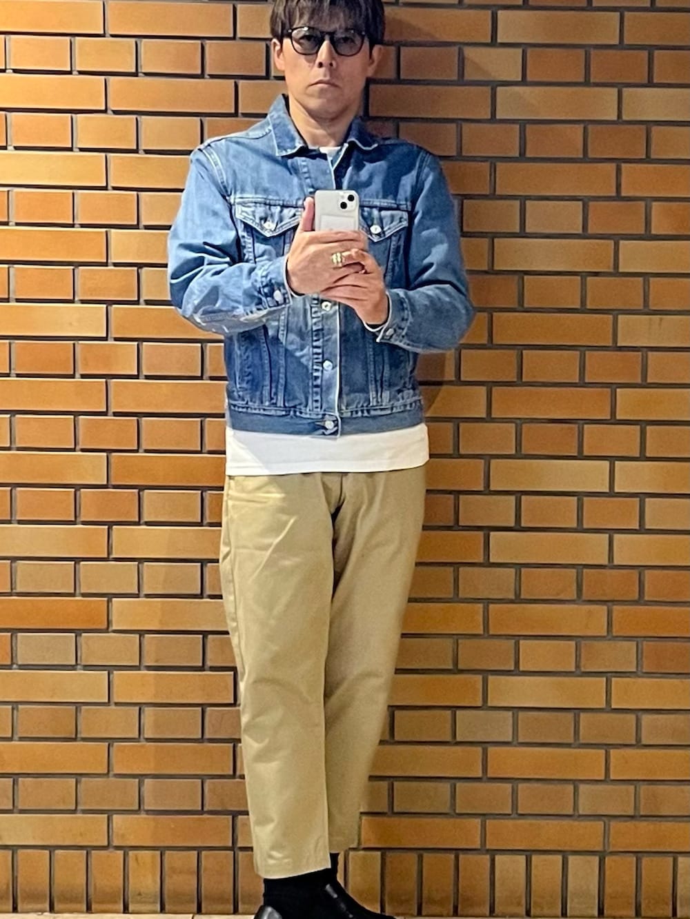 ベージュ系のチノパンツ、ブルー系のデニムジャケット、シルバー系のリングを着用したメンズの秋コーディネートの3枚目の写真