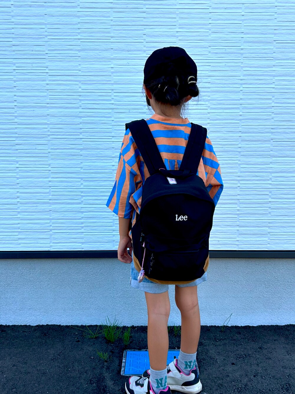 ブルー系のデニムパンツ、ブラック系のバックパック/リュック、オレンジ系のシャツ/ブラウスを着用したキッズの秋コーディネートの2枚目の写真