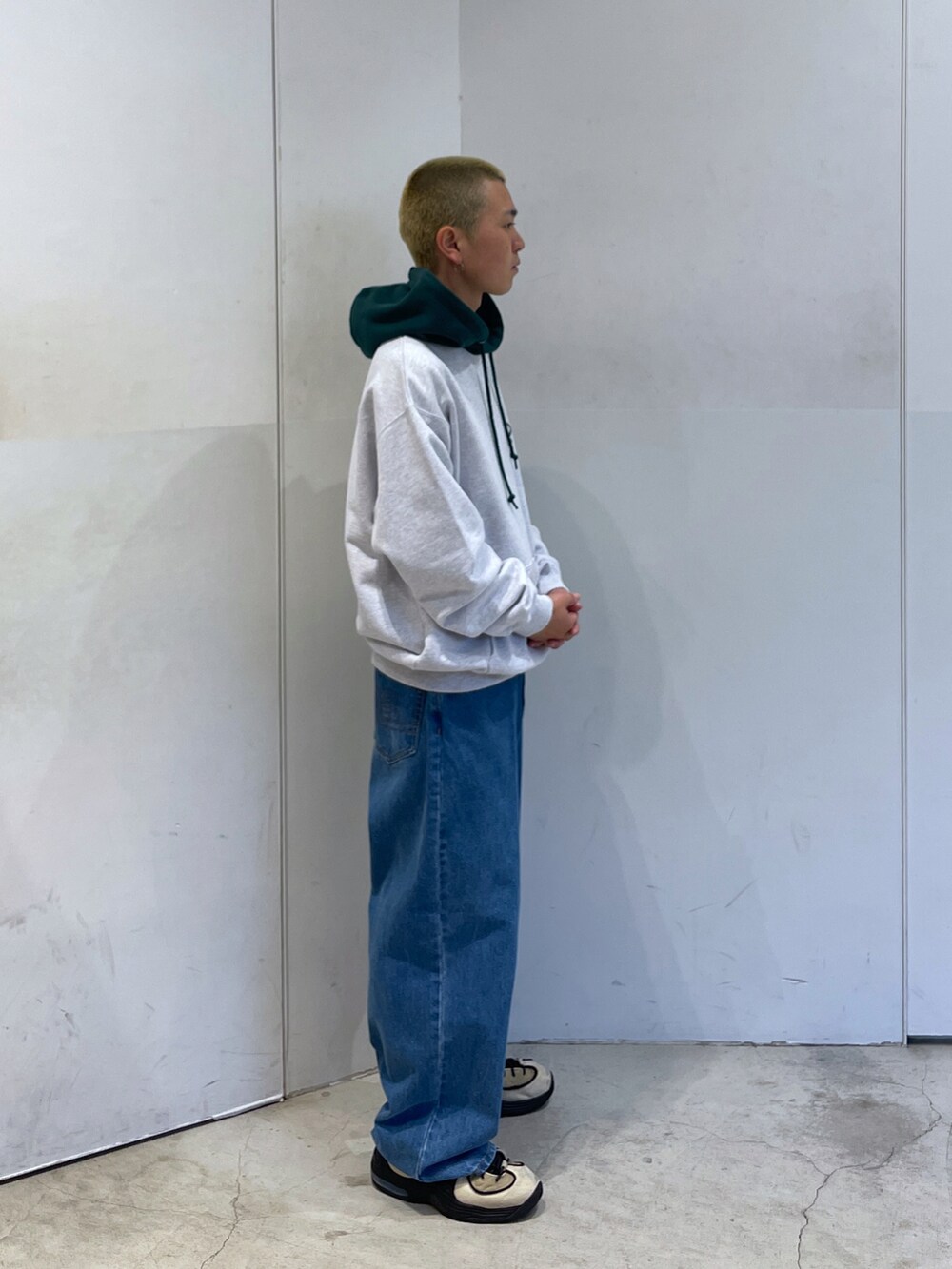 グレー系のパーカー、ブルー系のデニムパンツを着用したメンズの秋コーディネートの2枚目の写真