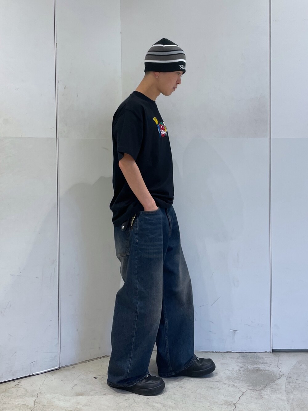 ブラック系のTシャツ/カットソー、ブルー系のデニムパンツ、ブラック系のニットキャップ/ビーニーを着用したメンズの春コーディネートの2枚目の写真