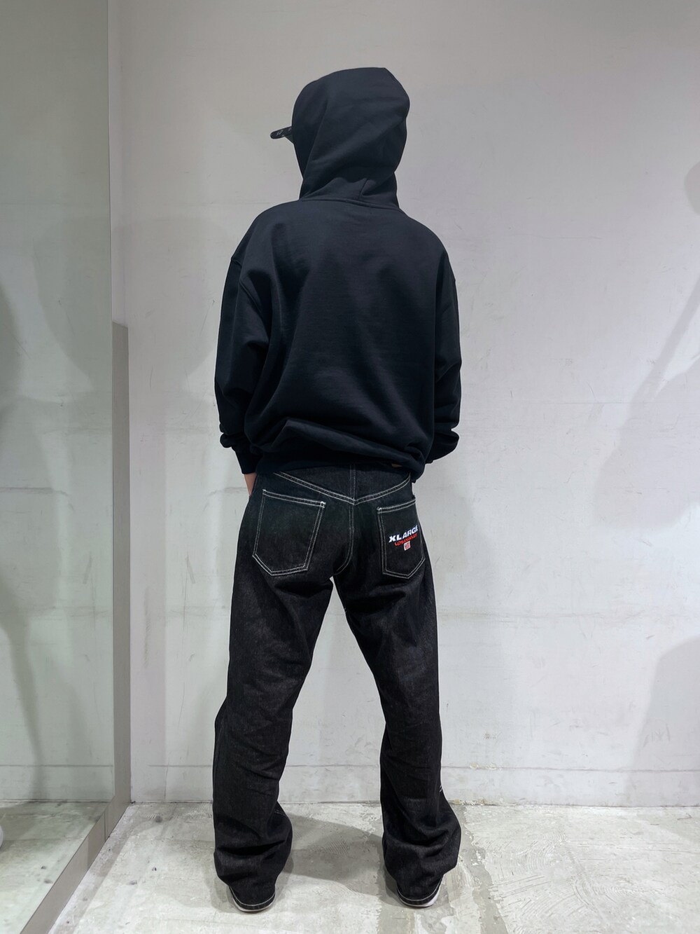 ブラック系のパーカー、ブラック系のパンツ、ホワイト系のキャップを着用したメンズの秋コーディネートの3枚目の写真