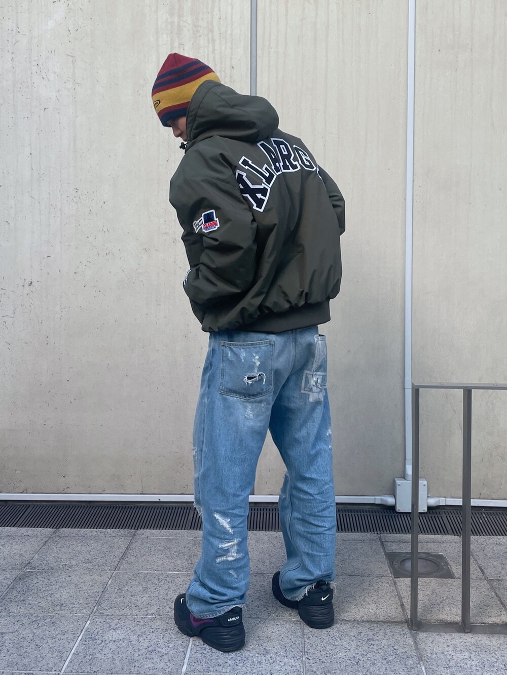 グリーン系のナイロンジャケット、ブルー系のデニムパンツ、レッド系のニットキャップ/ビーニーを着用したメンズの冬コーディネートの5枚目の写真