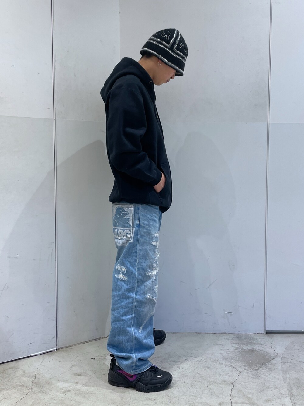 ブラック系のパーカー、ブルー系のデニムパンツ、ブラック系のハットを着用したメンズの冬コーディネートの2枚目の写真