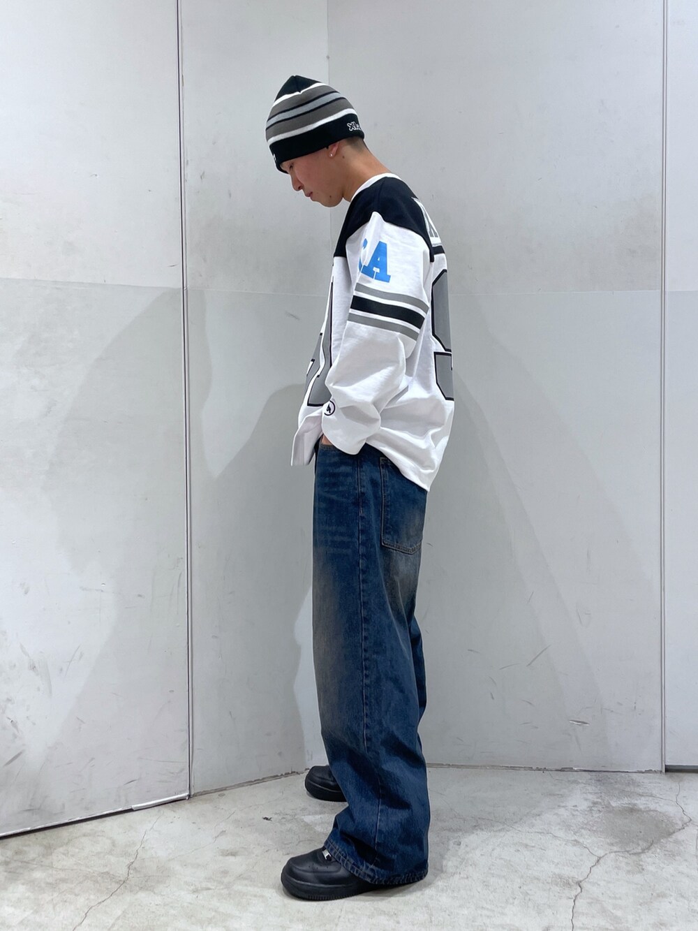 ホワイト系のTシャツ/カットソー、ブルー系のデニムパンツ、ブラック系のニットキャップ/ビーニーを着用したメンズの冬コーディネートの4枚目の写真