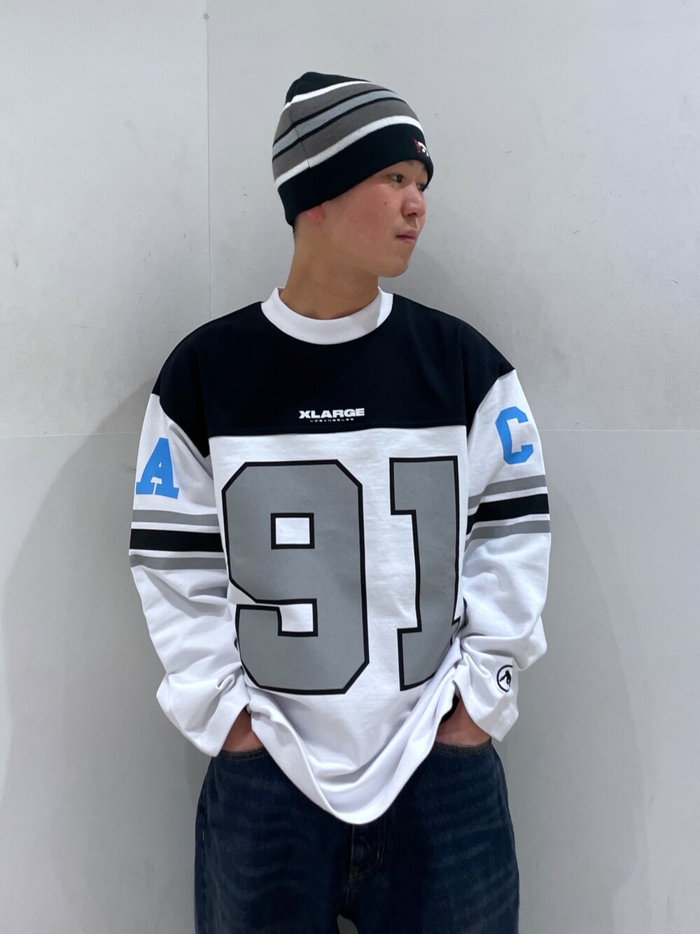 ホワイト系のTシャツ/カットソー、ブルー系のデニムパンツ、ブラック系のニットキャップ/ビーニーを着用したメンズの冬コーディネートの5枚目の写真