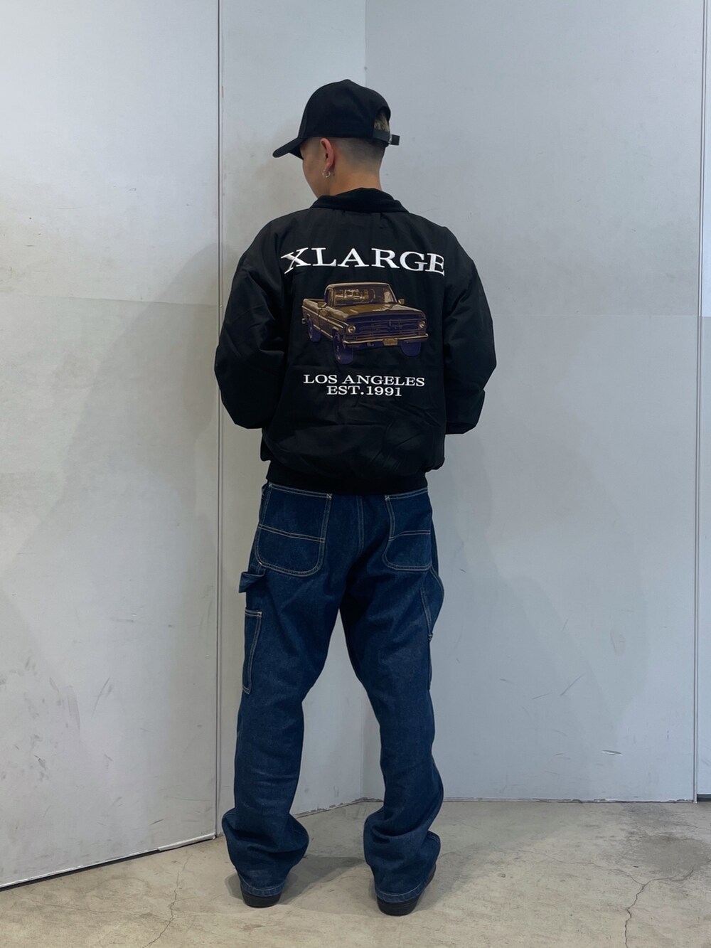 ブラック系のブルゾン、ブルー系のデニムパンツ、ブラック系のキャップを着用したメンズの秋コーディネートの3枚目の写真