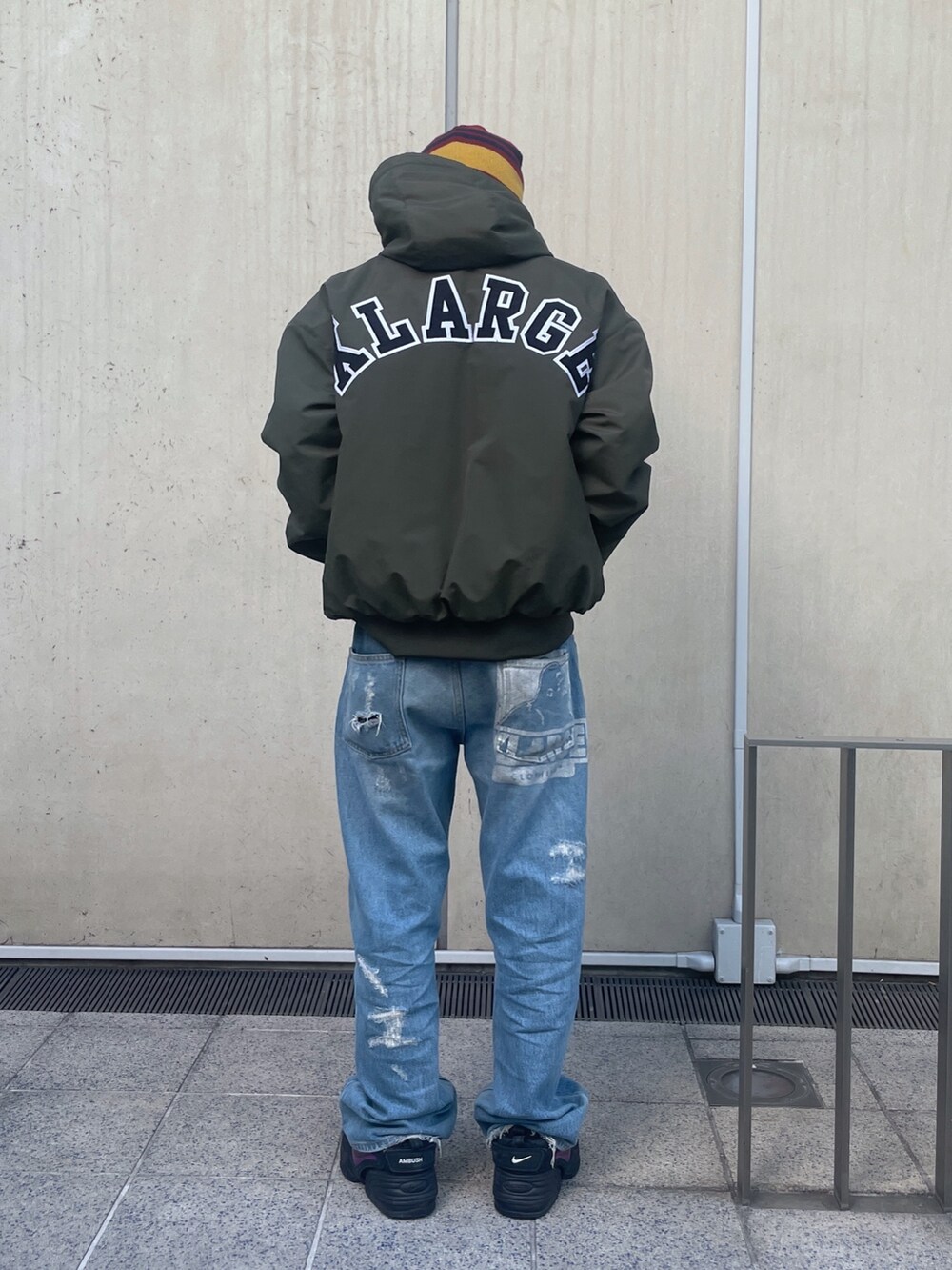 グリーン系のナイロンジャケット、ブルー系のデニムパンツ、レッド系のニットキャップ/ビーニーを着用したメンズの冬コーディネートの3枚目の写真