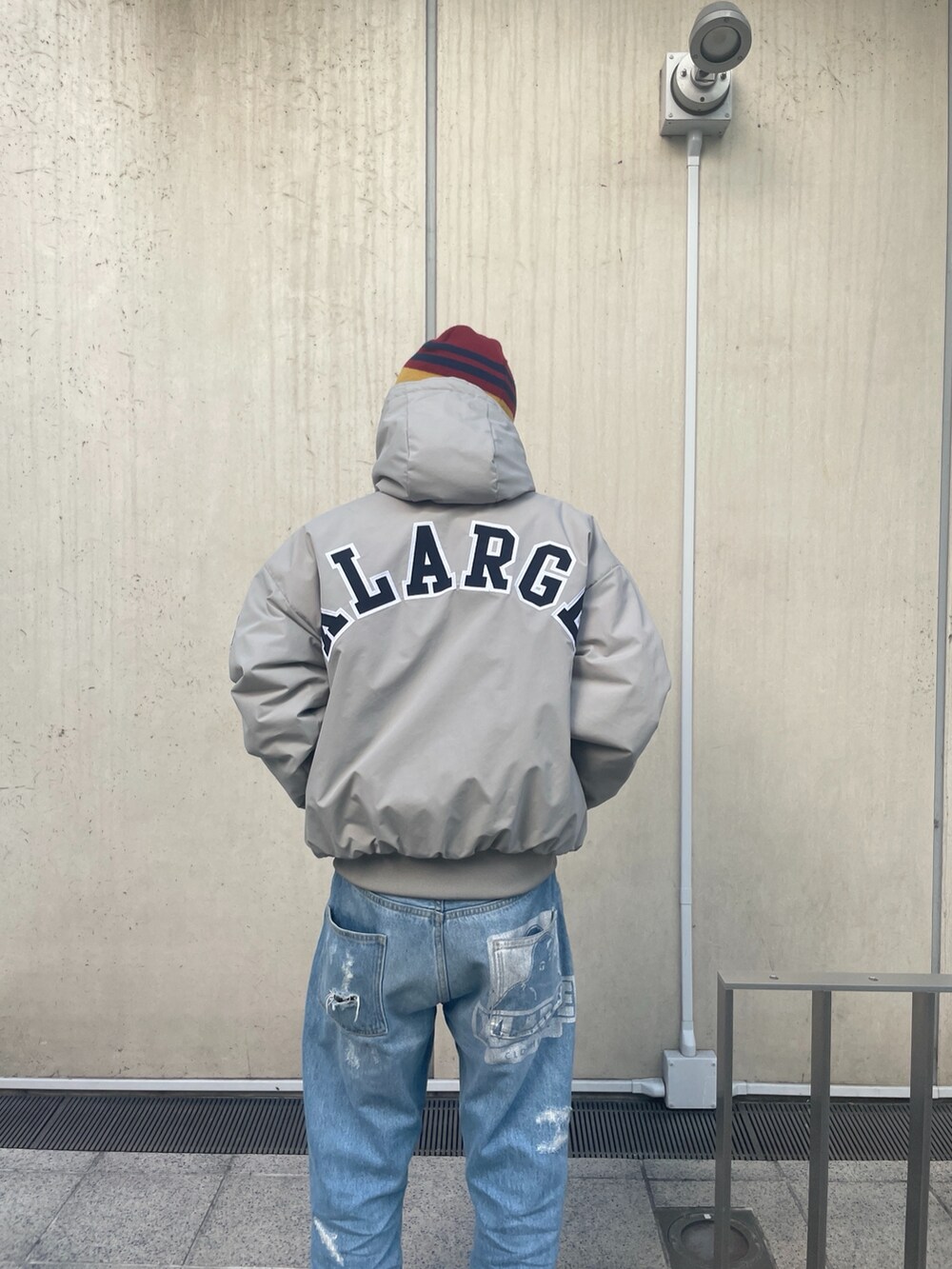 グレー系のナイロンジャケット、ブルー系のデニムパンツ、レッド系のニットキャップ/ビーニーを着用したメンズの冬コーディネートの9枚目の写真