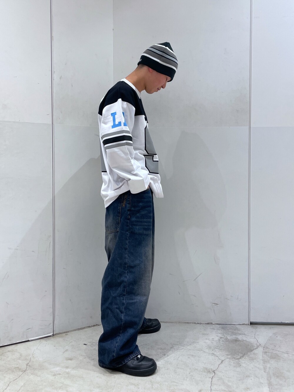 ホワイト系のTシャツ/カットソー、ブルー系のデニムパンツ、ブラック系のニットキャップ/ビーニーを着用したメンズの冬コーディネートの2枚目の写真