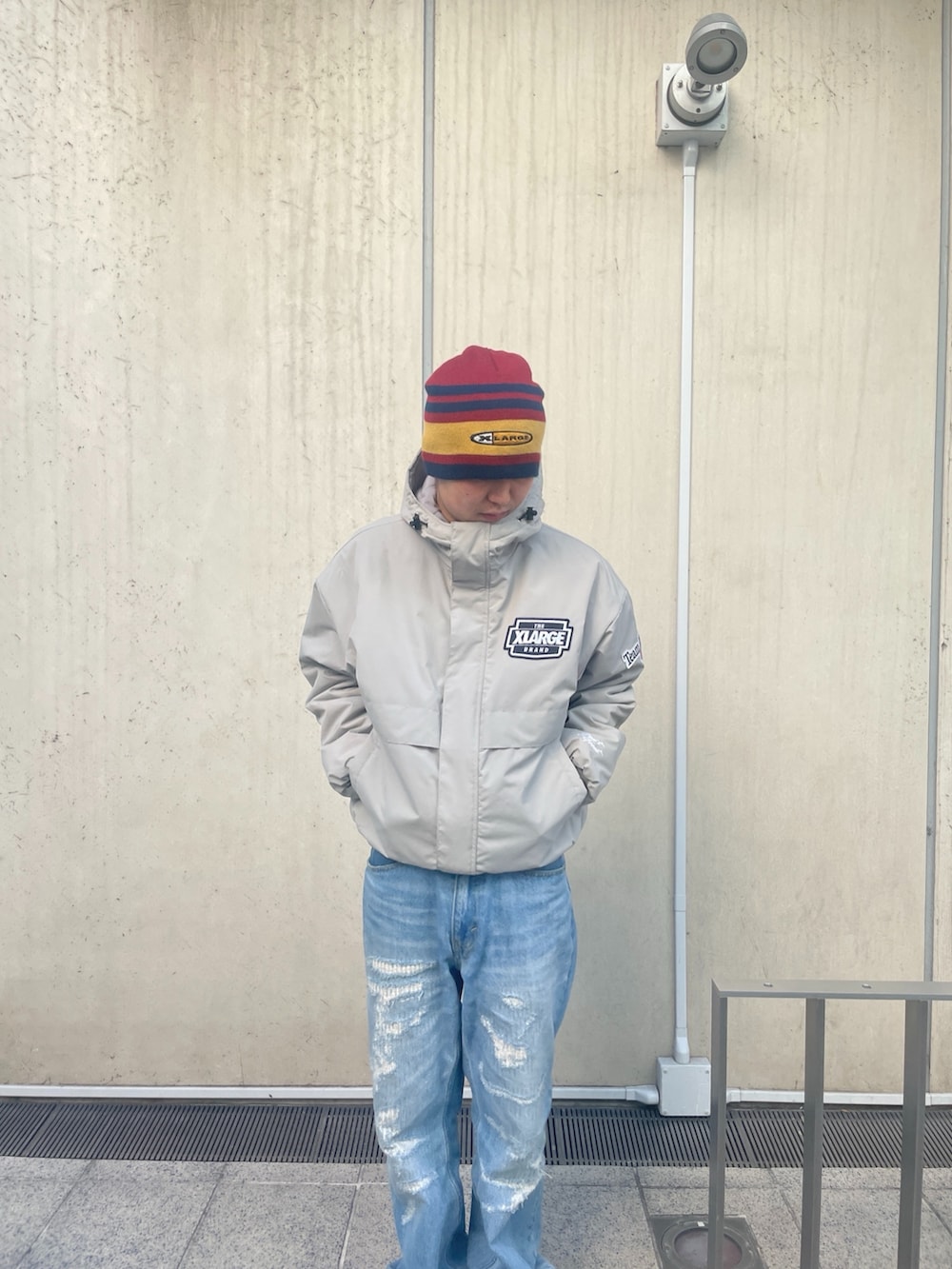 グレー系のナイロンジャケット、ブルー系のデニムパンツ、レッド系のニットキャップ/ビーニーを着用したメンズの冬コーディネートの7枚目の写真