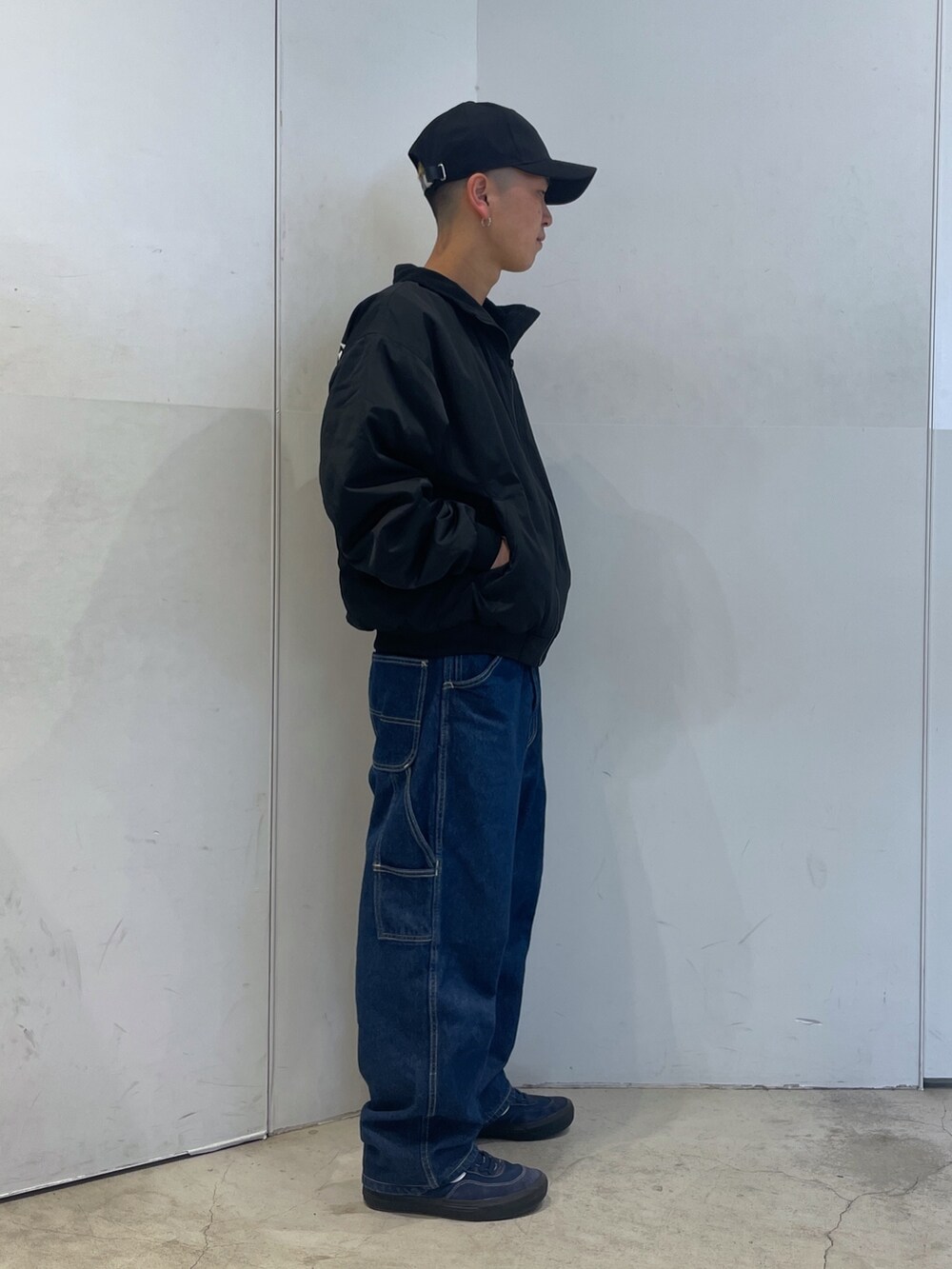 ブラック系のブルゾン、ブルー系のデニムパンツ、ブラック系のキャップを着用したメンズの秋コーディネートの2枚目の写真