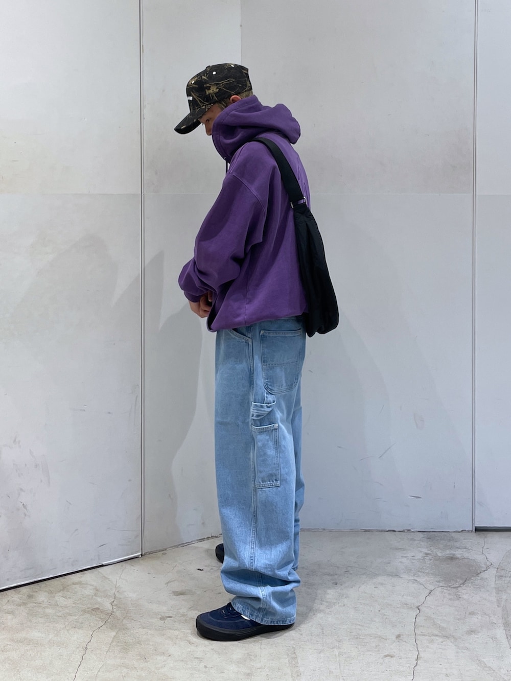 パープル系のパーカー、ブルー系のデニムパンツ、ブラック系のショルダーバッグを着用したメンズの秋コーディネートの3枚目の写真