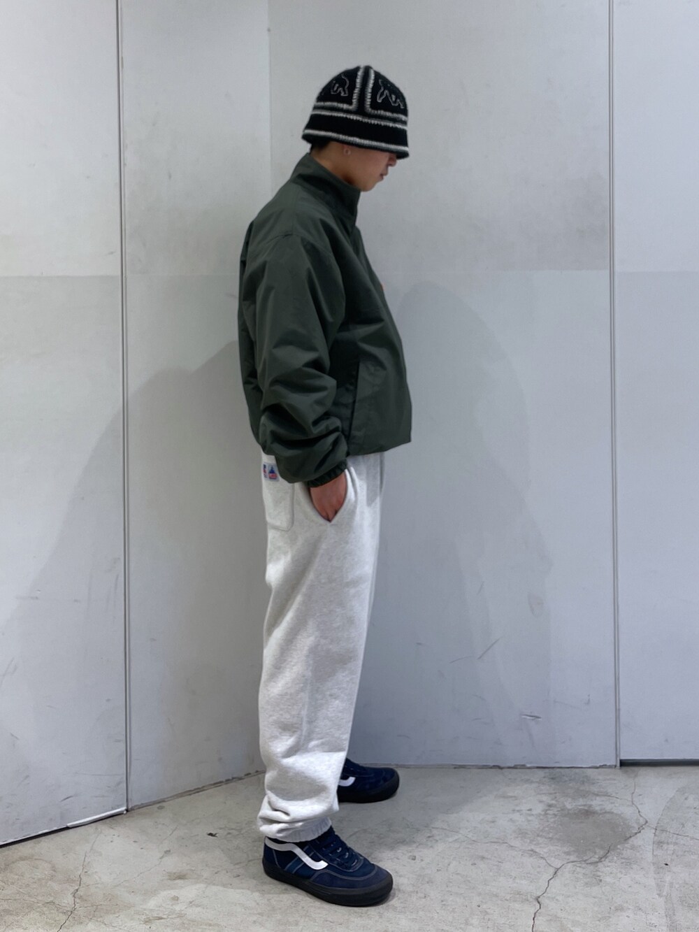 グリーン系のブルゾン、グレー系のスウェットパンツ、ブラック系のハットを着用したメンズの冬コーディネートの2枚目の写真